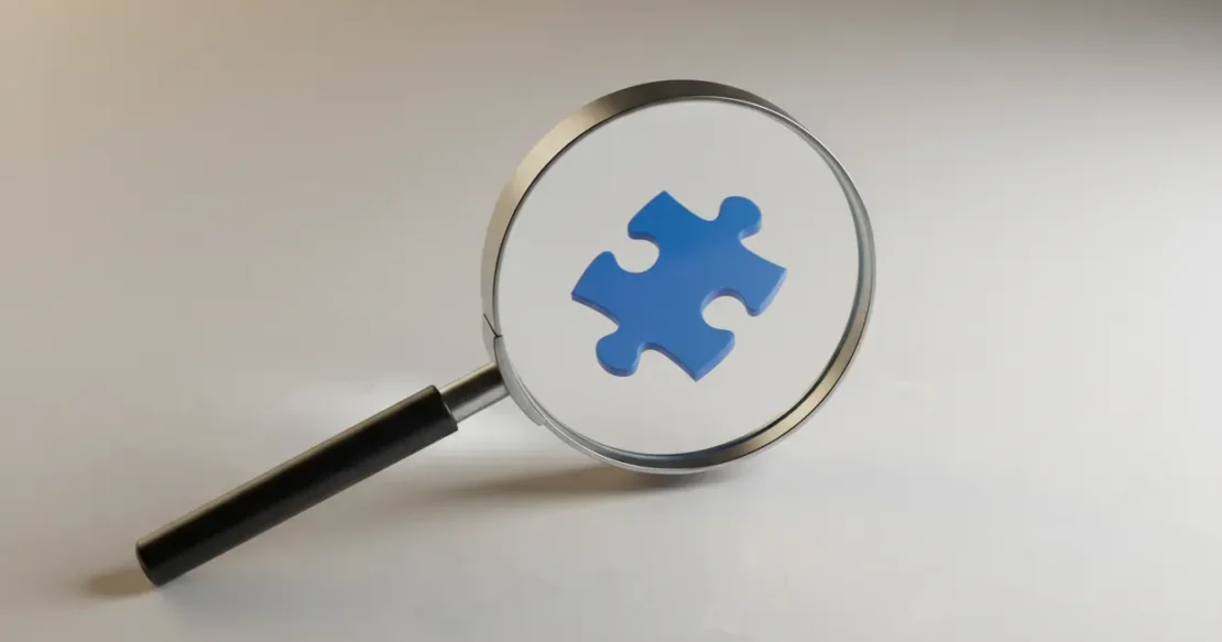 Magnifying glass highlighting a lone blue puzzle piece on a neutral background, symbolizing a missed question in competitor research.