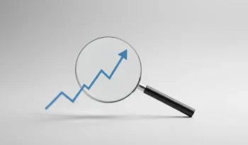 Magnifying glass revealing a sharp upward trend line on a soft, neutral background.